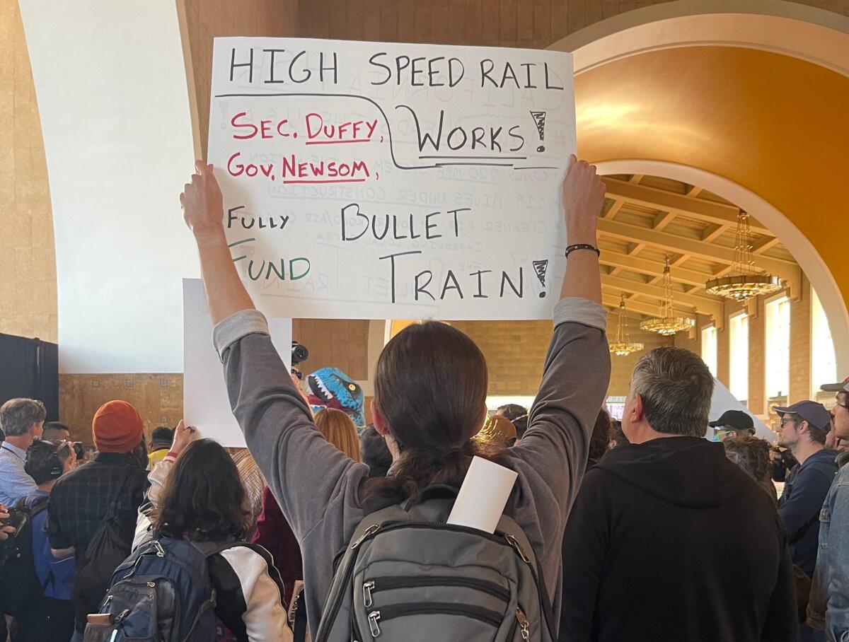 Manifestantes sostienen carteles durante la conferencia de prensa en Union Station el 20 de febrero de 2025. (Beige Luciano-Adams/The Epoch Times).