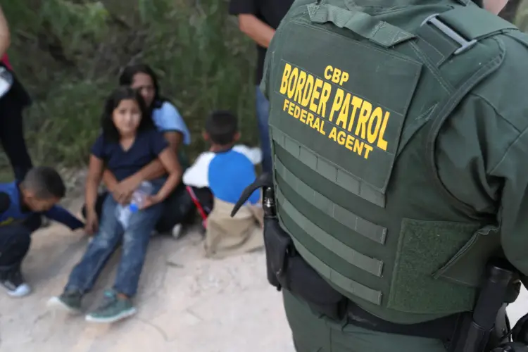 Solicitantes de asilo centroamericanos esperan mientras agentes de la Patrulla Fronteriza de EE. UU. los ponen bajo custodia el 12 de junio de 2018 cerca de McAllen, Texas. (John Moore/Getty Images)