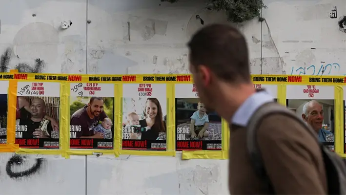 Un hombre pasa junto a las fotos de Yarden Bibas, Shiri Bibas y Kfir Bibas en Jerusalén, Israel, el 19 de febrero de 2025. (Ronen Zvulun/Reuters)
