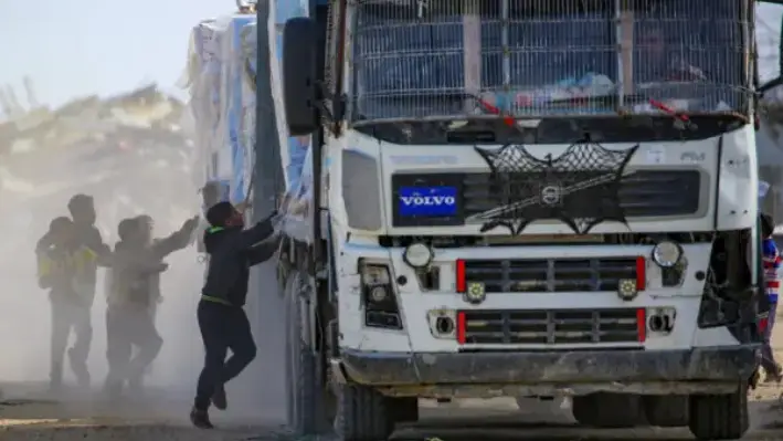 Niños palestinos intentan sacar paquetes de ayuda humanitaria de un camión mientras atraviesa Rafah, en el sur de la Franja de Gaza, después de cruzar el paso fronterizo de Kerem Shalom, el 18 de febrero de 2025. (EYAD BABA/AFP a través de Getty Images)