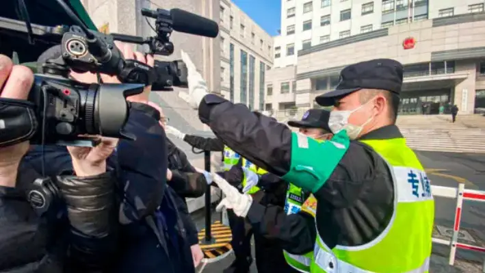 Un policía tapa una cámara para impedir que los periodistas graben imágenes fuera de la Corte Popular del Nuevo Distrito de Pudong de Shanghái, donde el periodista ciudadano chino Zhang Zhan sería juzgado en Shanghái, el 28 de diciembre de 2020. (Leo Ramírez/AFP a través de Getty Images)