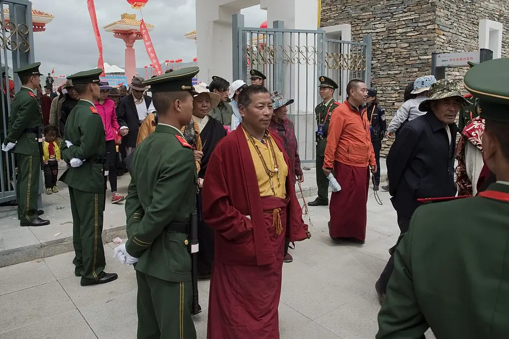 La policía paramilitar china (con uniformes verdes) asegura una salida mientras los monjes tibetanos (C) salen de un estadio al final de un festival patrocinado por el gobierno local en Yushu, en la provincia de Qinghai, en el noroeste de China, el 25 de julio de 2016. (Nicolas Asfouri/AFP a través de Getty Images)