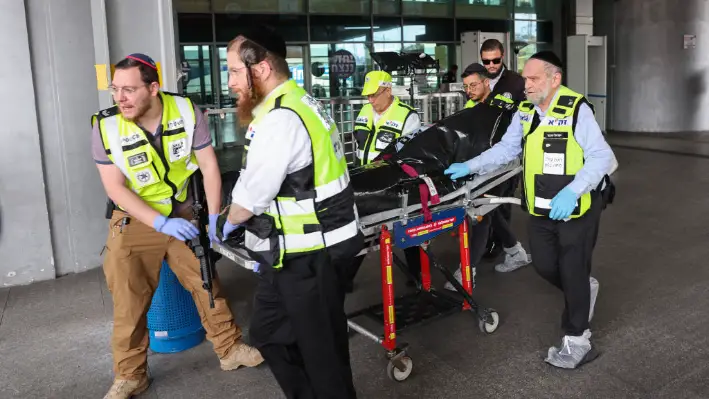 Miembros de los servicios de seguridad y emergencia israelíes transportan el cuerpo del supuesto atacante al lugar del apuñalamiento en una estación central de autobuses en Haifa el 3 de marzo de 2025. (Jack Guez/AFP vía Getty Images)