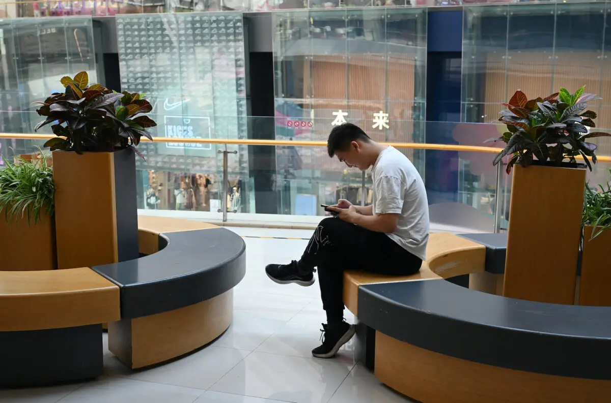 Un hombre consulta su teléfono mientras descansa en un centro comercial de Beijing, el 18 de julio de 2023. (Greg Baker/AFP a través de Getty Images)