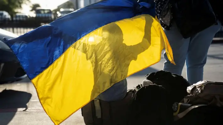 Un niño ucraniano que busca asilo en Estados Unidos juega con una bandera ucraniana después de llegar al cruce fronterizo de PedWest en el puerto de entrada de San Ysidro, en San Diego, California, el 13 de abril de 2022. (Reuters)