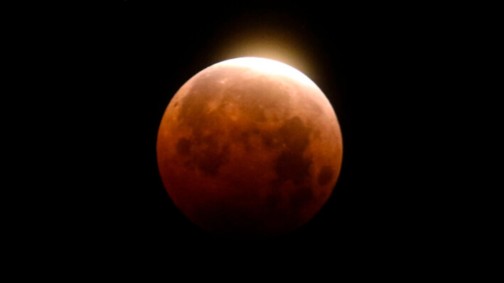 La luz brilla desde un eclipse lunar total sobre la playa de Santa Mónica, en California, el 26 de mayo de 2021. (Ringo H.W. Chiu/AP Photo).