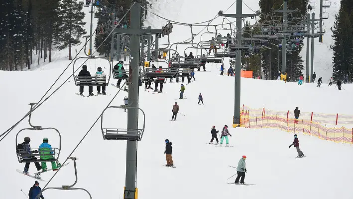 La gente sube a un telesilla mientras los esquiadores y practicantes de snowboard pasan por debajo en Red Lodge Mountain, 20 de febrero de 2023, cerca de Red Lodge, Montana. (Larry Mayer/The Billings Gazette vía AP).