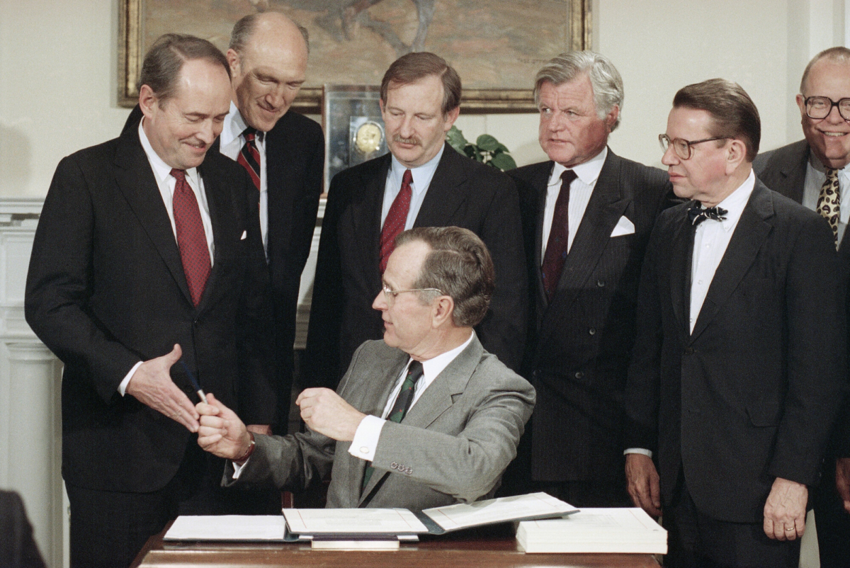 El presidente George H. Bush entrega un bolígrafo al fiscal general Dick Thornburgh, a la izquierda, después de que este promulgara una ley de inmigración, el 29 de noviembre de 1990, en Washington, en la Casa Blanca. De izquierda a derecha, están Thornburgh, el senador Alan Simpson (R-Wyo.), el representante Bruce Morrison, (D-Conn.), Edward Kennedy, (D-Mass.), y el senador Paul Simon, (D-Ill.). (Foto AP/Marcy Nighswander, archivo)