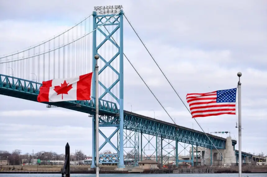 Banderas canadienses y estadounidenses ondean cerca del puente Ambassador en el cruce fronterizo entre Canadá y Estados Unidos en Windsor, Ontario, el 21 de marzo de 2020. The Canadian Press/Rob Gurdebeke