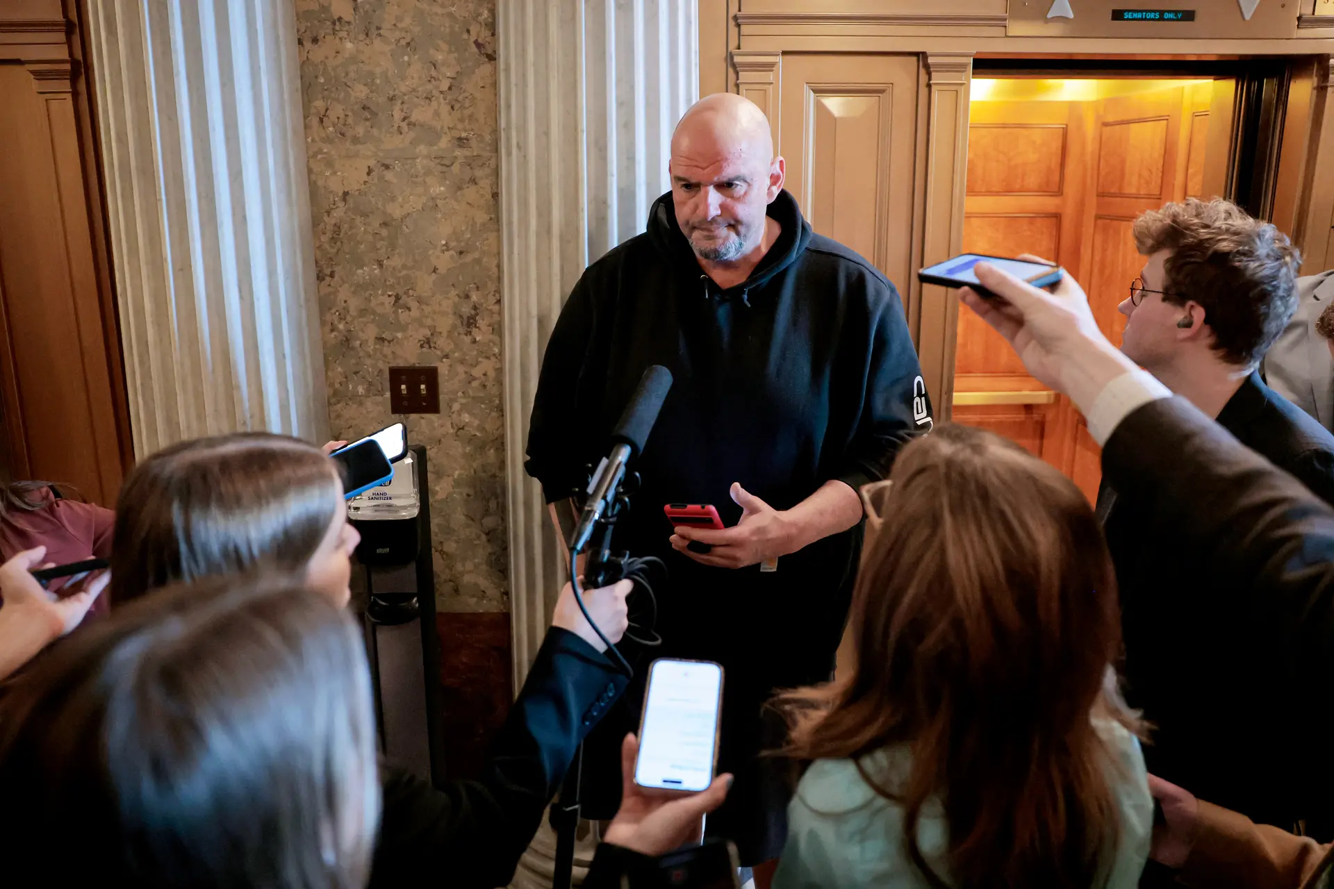 El senador John Fetterman (D-Pa.) habla con los periodistas fuera de las Cámaras del Senado en el Capitolio de los Estados Unidos el 13 de marzo de 2025. Fetterman dice que, con el control republicano del Senado, su influencia sobre el DOGE está restringida, hasta que sus efectos se filtren a los electores en los estados rojos. (Anna Moneymaker/Getty Images)