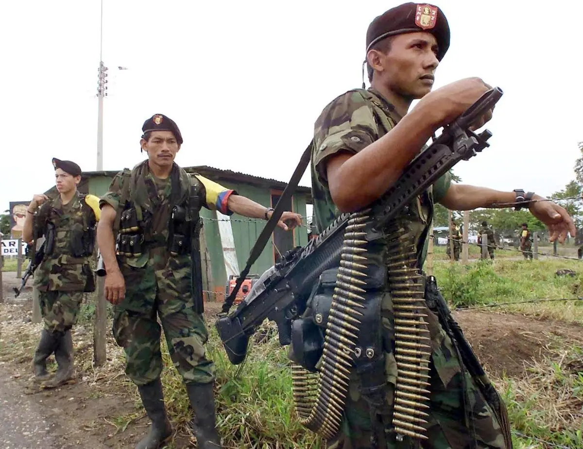 <em>Guerrilleros de las Fuerzas Armadas Revolucionarias de Colombia (FARC) custodian el lugar donde se llevaron a cabo las conversaciones entre Manuel Marulanda, jefe rebelde marxista de las FARC, y el entonces presidente colombiano Andrés Pastrana, en febrero de 2001. Luis Acosta/AFP vía Getty Images</em>