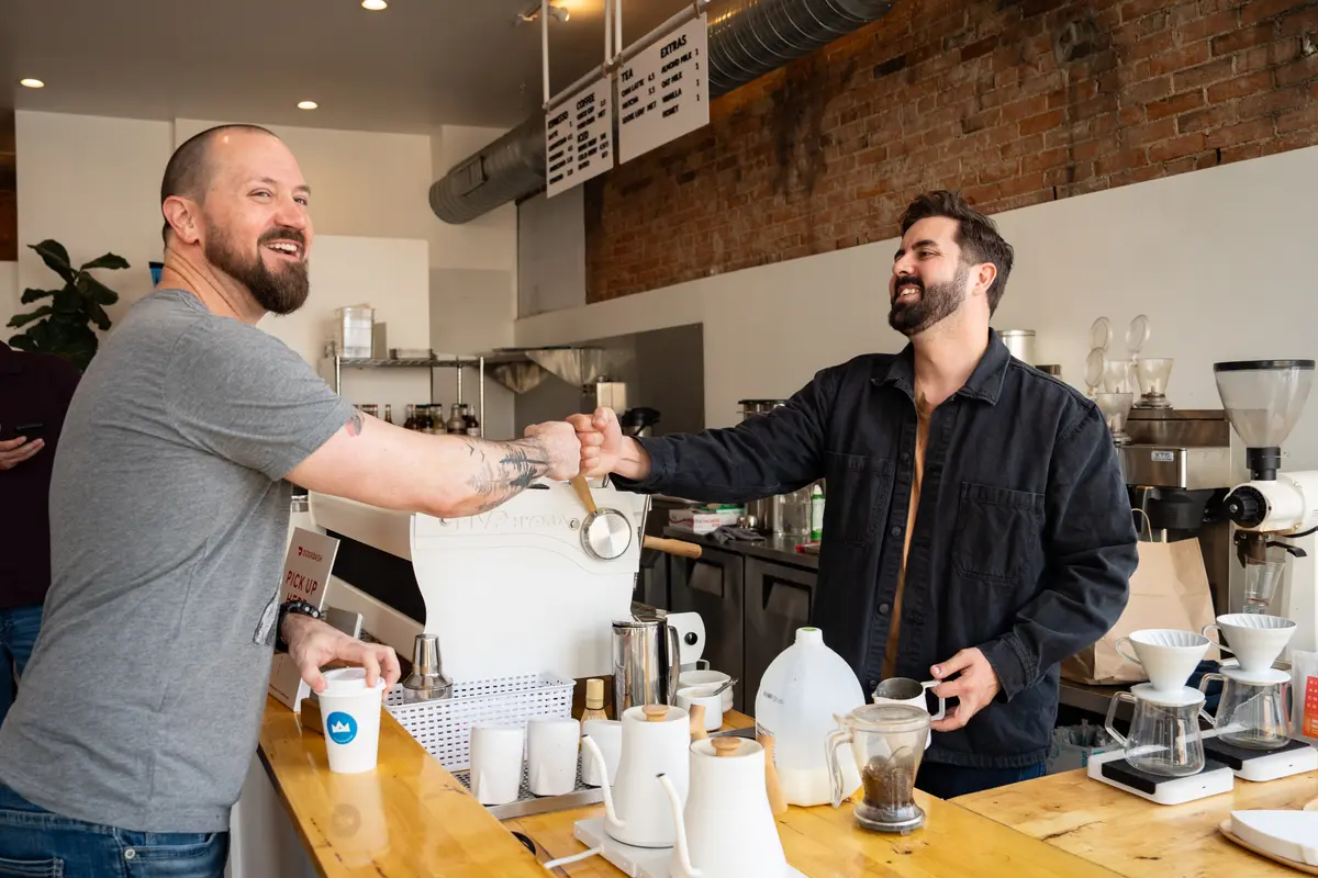 El candidato a la alcaldía de Cincinnati, Cory Bowman, saluda a un cliente en su cafetería de Cincinnati el 25 de abril de 2025. (Samira Bouaou/The Epoch Times)