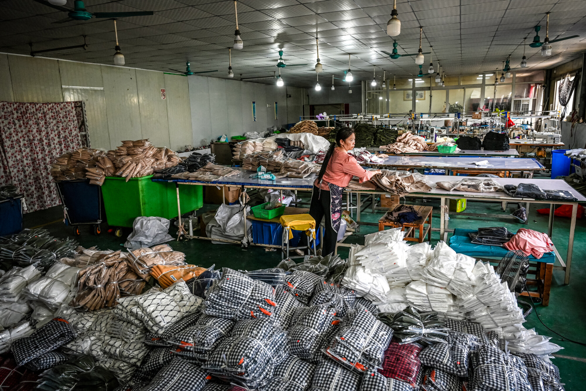 Un empleado empaqueta prendas para la empresa china de comercio electrónico Temu en una fábrica de ropa en Guangzhou, provincia de Guangdong, China, el 16 de abril de 2025. Los trabajadores de la fábrica afirman que muchos pedidos con destino a Estados Unidos siguen bloqueados en contenedores. (Cheng Xin/Getty Images, Jade Gao/AFP a través de Getty Images).