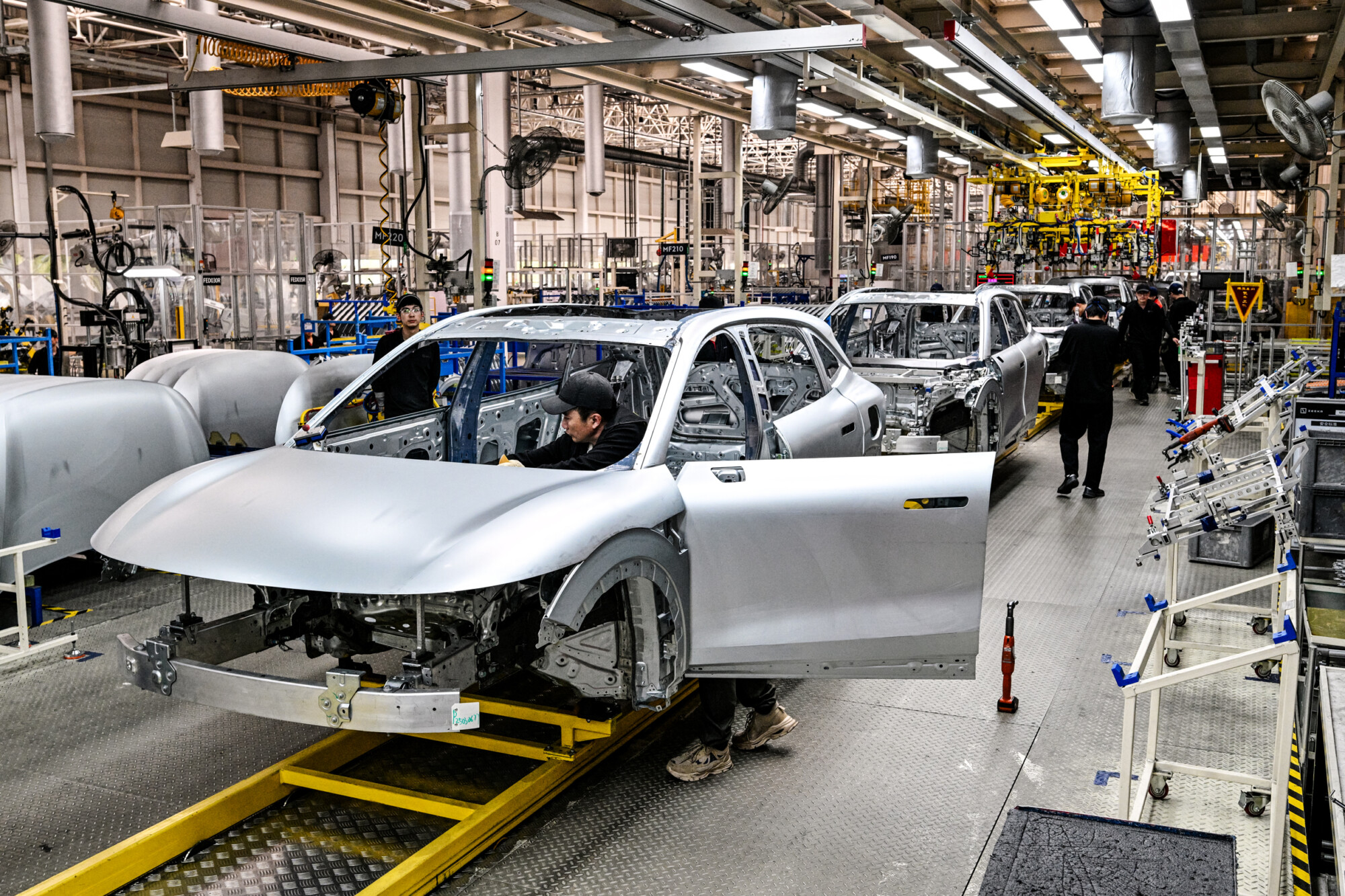 Trabajadores inspeccionan los coches eléctricos Zeekr 7X en una fábrica de Zeekr en la isla de Meishan, en Ningbo, provincia de Zhejiang (China), el 18 de abril de 2025. (Hector Retamal/AFP a través de Getty Images, Kevin Frayer/Getty Images).