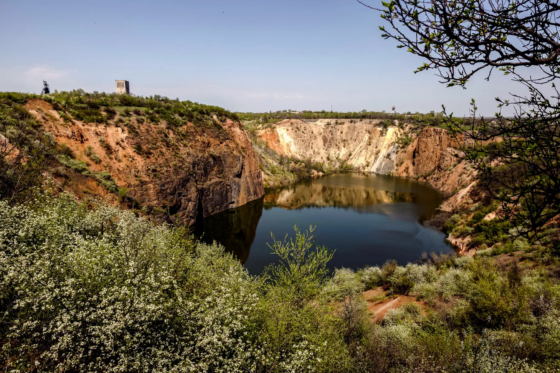 Las flores crecen alrededor de una mina a cielo abierto inundada, legado de la industria del uranio de la Unión Soviética, en medio del ataque de Rusia a Ucrania, en Zhovti Vody, Ucrania, el 24 de abril de 2025. (Thomas Peter/Reuters).