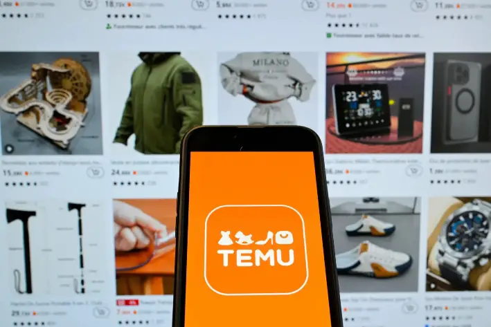 El logotipo de la empresa china de comercio electrónico Temu se ve en un teléfono móvil delante de su página web en Bruselas, el 4 de noviembre de 2024. Shein y Temu se han convertido en gigantes mundiales del comercio electrónico al vender directamente a los consumidores productos chinos de bajo coste. (Nicolas Tucat/AFP vía Getty Images)