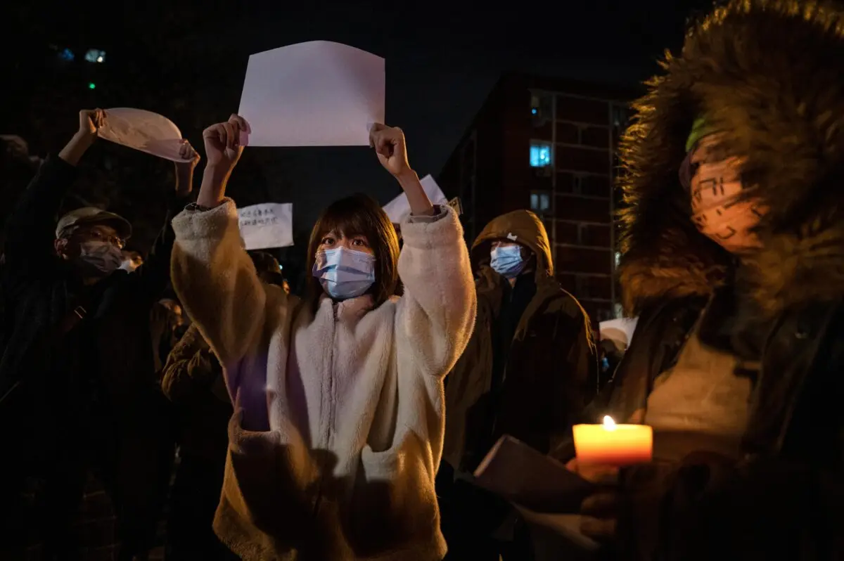 Manifestantes sostienen una hoja de papel en blanco en contra de la censura mientras marchan durante una protesta contra la estricta política de COVID cero de China en Beijing, el 27 de noviembre de 2022. (Kevin Frayer/Getty Images).