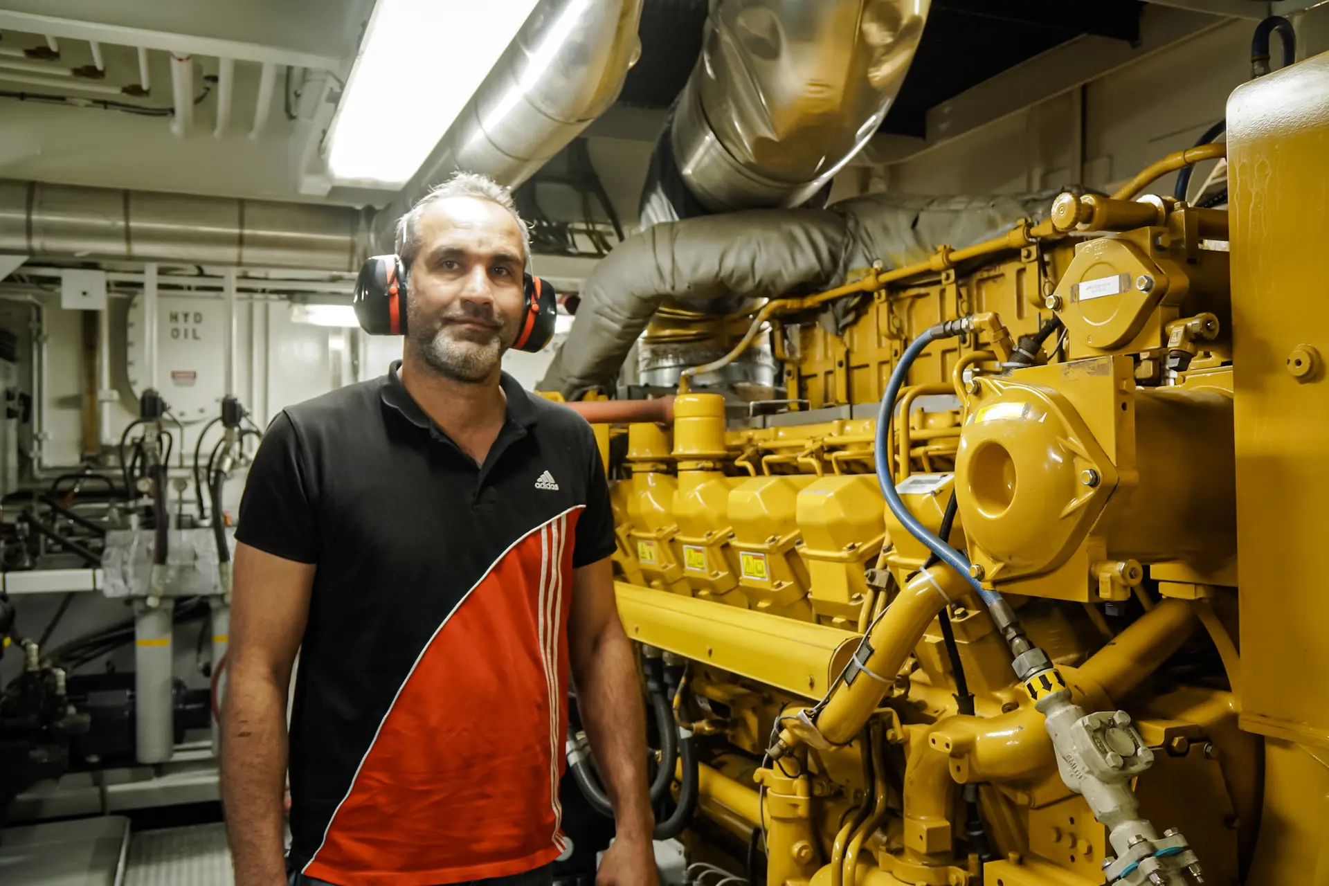 William Suwaed, ingeniero jefe de Vane Brothers a bordo del remolcador Fishing Creek, explica el funcionamiento de uno de los dos motores diésel que propulsan el remolcador, el 8 de abril de 2025. (Allan Stein/The Epoch Times)