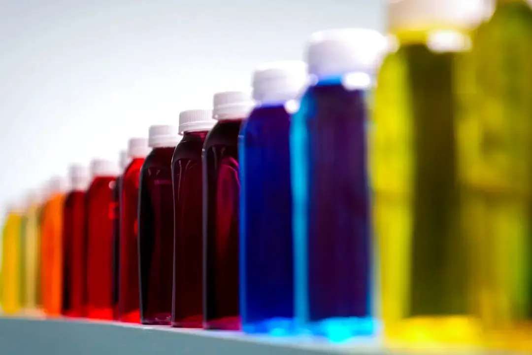 Botellas que contienen una variedad de líquidos de colores en una estantería de un laboratorio de Sensient Technologies Corp., una empresa fabricante de aditivos colorantes, en St. Louis, el 2 de abril de 2025. (AP Photo/Jeff Roberson)