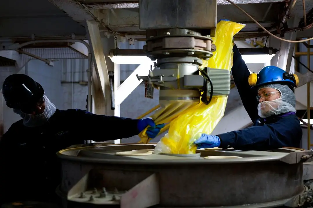 Jobe Washington y Dwight Brown utilizan un gran tamiz para mezclar un tono de color amarillo en Sensient Technologies Corp., una empresa de fabricación de aditivos colorantes, en St. Louis, el 2 de abril de 2025. (Jeff Roberson/AP Photo)