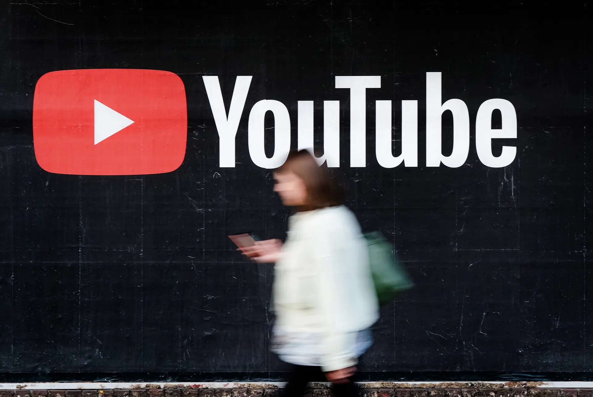 Una joven con un smartphone pasa junto a una valla publicitaria de YouTube en Berlín, Alemania, el 27 de septiembre de 2019. (Sean Gallup/Getty Images).