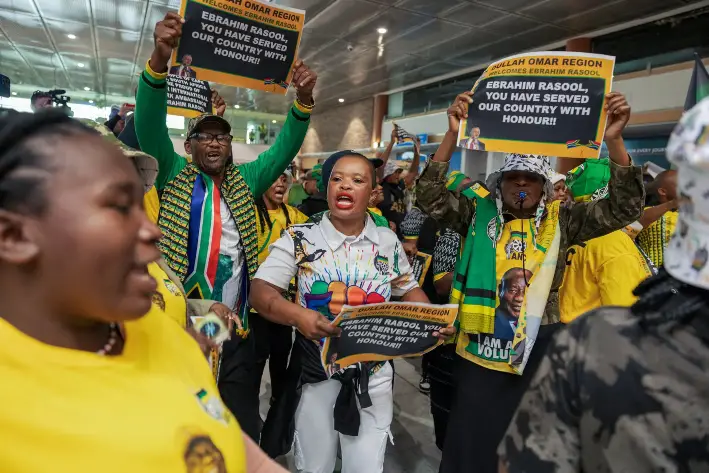 Miembros del Congreso Nacional Africano, del Partido Comunista Sudafricano y de sindicatos sudafricanos cantan y bailan mientras esperan la llegada del exembajador sudafricano en Estados Unidos, Ebrahim Rasool, al aeropuerto internacional de Ciudad del Cabo, en Sudáfrica, el 23 de marzo de 2025. (Gianluigi Guercia/AFP a través de Getty Images)