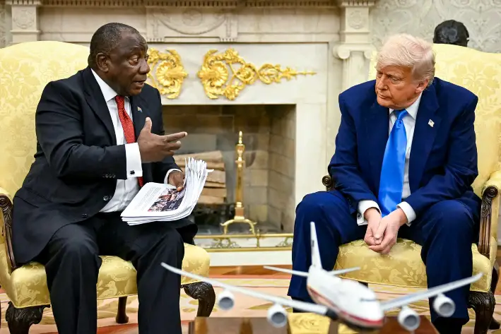 El presidente Donald Trump entrega documentos al presidente sudafricano Cyril Ramaphosa durante una reunión en el Despacho Oval de la Casa Blanca, el 21 de mayo de 2025. (Jim Watson/AFP a través de Getty Images)