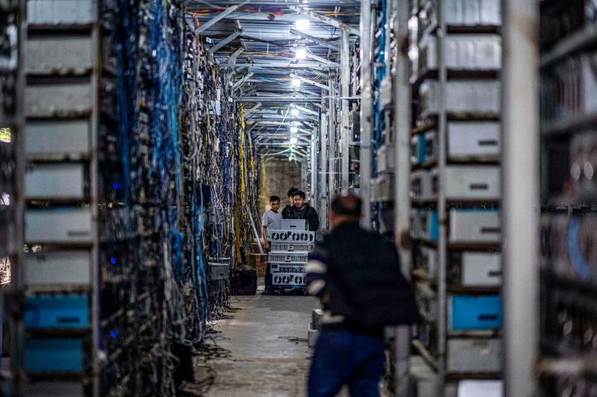 Trabajadores transfieren equipos de minería de criptomonedas en una granja de criptomonedas, que cuenta con más de 3000 equipos de minería, en Dujiangyan, provincia de Sichuan, China, el 31 de marzo de 2021. (STR/AFP a través de Getty Images)