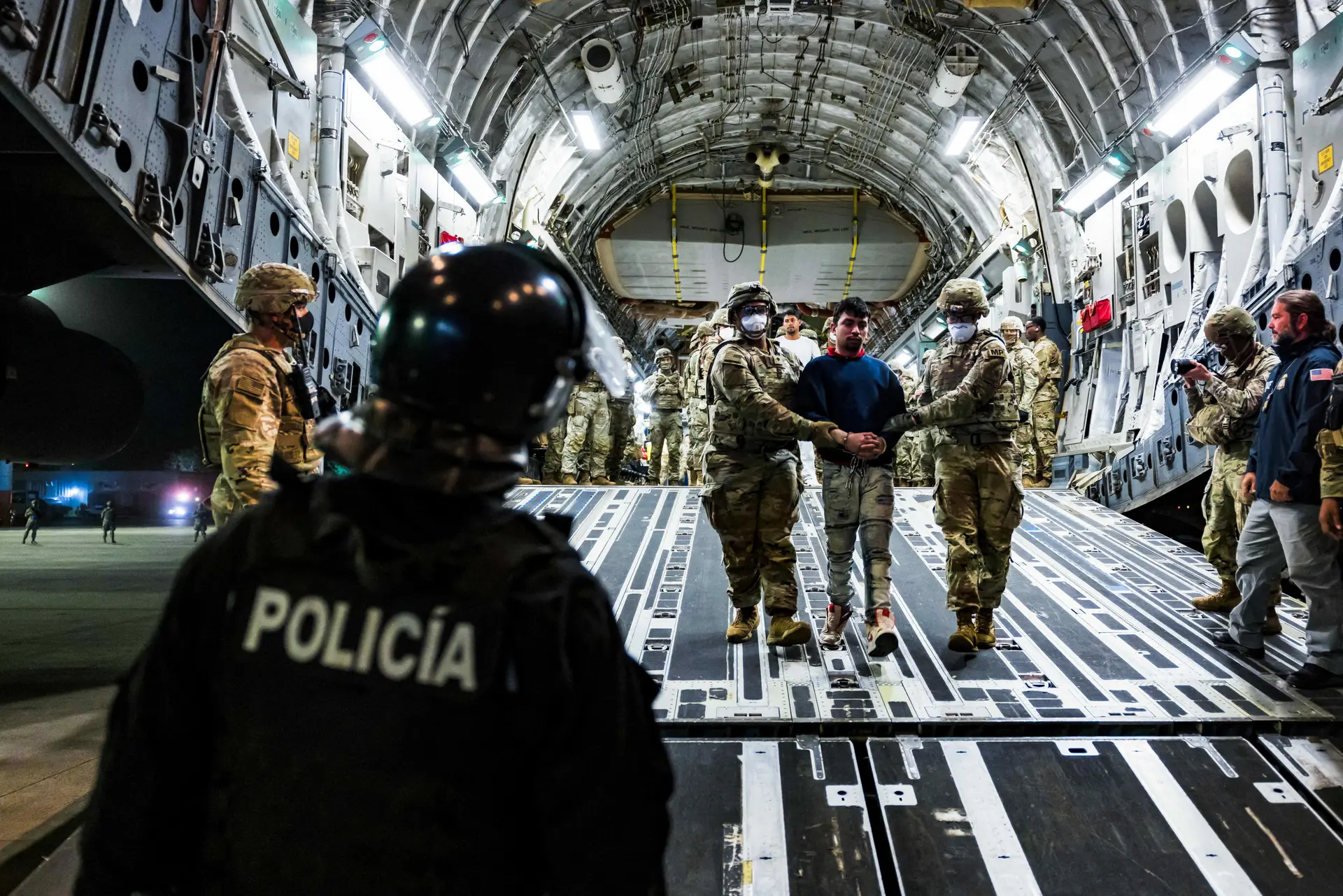 Personal militar estadounidense escolta a presuntos miembros de la banda venezolana Tren de Aragua y la banda MS-13 recientemente deportados por el Gobierno de Estados Unidos para ser encarcelados en el Centro de Confinamiento por Terrorismo (CECOT), en el Aeropuerto Internacional de El Salvador, en San Luis Talpa, El Salvador, el 12 de abril de 2025. (Secretaria de Prensa de la Presidencia/Handout vía Reuters).