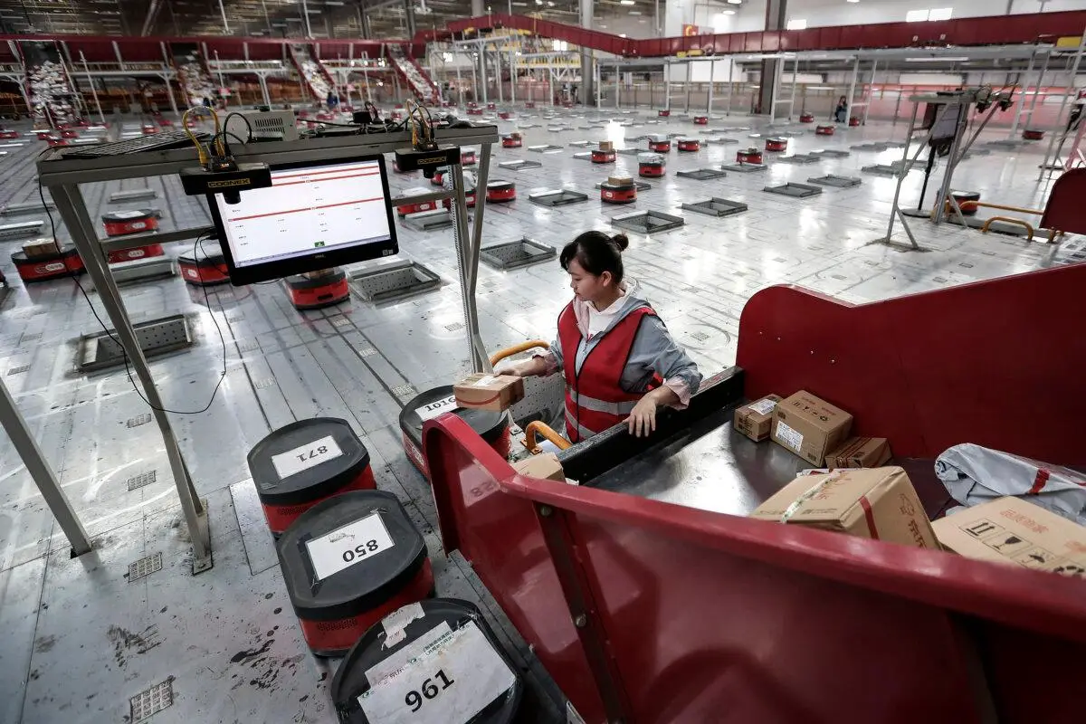 Un empleado traslada paquetes de una cinta transportadora a un robot automático en el almacén de una base logística del Grupo JingDong en Wuhan, provincia de Hubei, China, el 5 de noviembre de 2019. (Wang He/Getty Images)