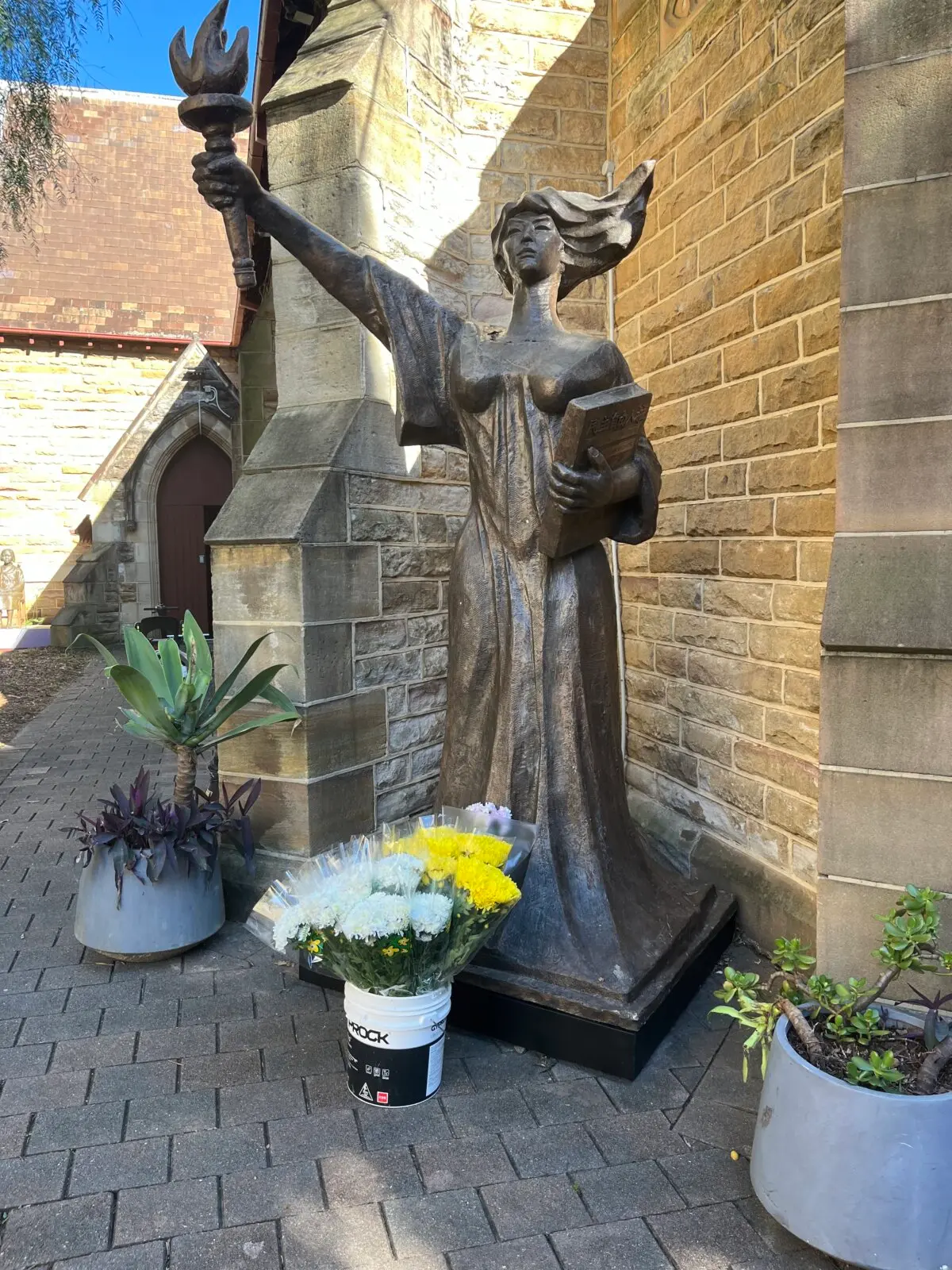 Se depositaron flores ante la estatua de la Diosa de la Democracia antes de un foro conmemorativo del 36.º aniversario de la masacre de la plaza de Tiananmen, celebrado en la Iglesia Uniting de Ashfield, en Sídney, el 1 de junio de 2025. (Cindy Li/The Epoch Times).