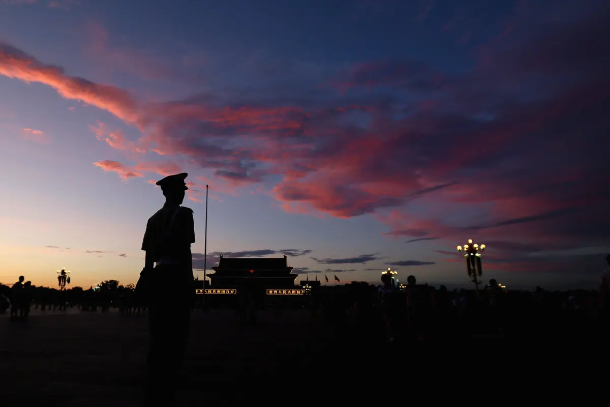 Un policía paramilitar chino vigila la plaza de Tiananmen bajo nubes carmesí al atardecer, tras varios días de fuerte contaminación atmosférica, en Beijing, China, el 4 de julio de 2013. (Feng Li/Getty Images)