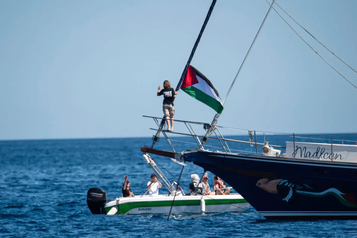 La activista climática Greta Thunberg junto a una bandera palestina en el velero Madleen en el puerto de Catania, Italia, el 1 de junio de 2025. (Salvatore Cavalli/AP)