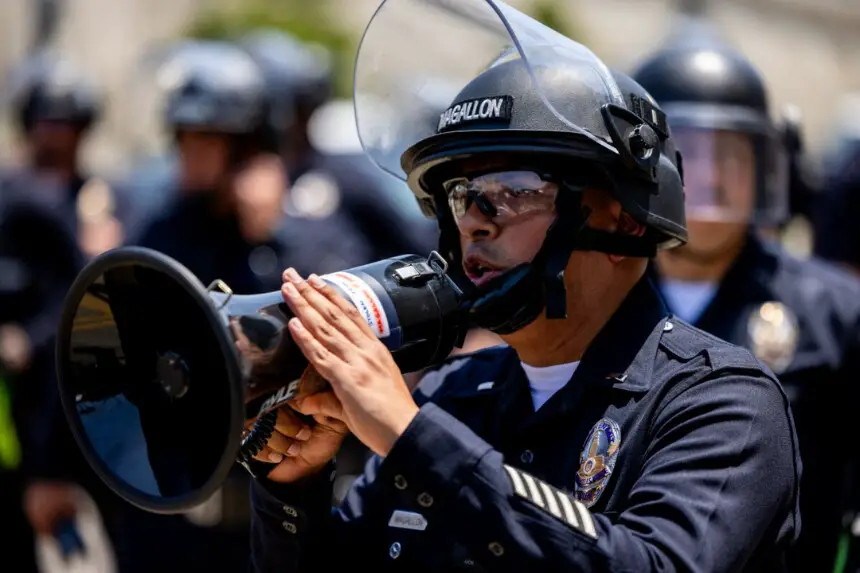 Un oficial de policía de Los Ángeles ruega a la multitud que abandone la calle frente al Centro de Detención Metropolitano, en el centro de Los Ángeles, California, el 9 de junio de 2025. (Benjamin Hanson/Middle East Images vía AFP).