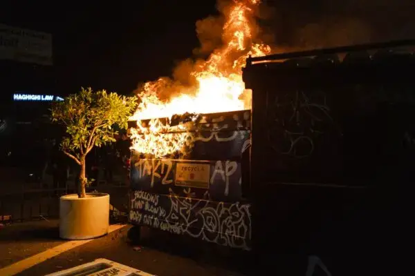 Manifestantes incendian un contenedor de basura durante las clases con la policía en el centro de Los Ángeles el 8 de junio de 2025. (Jim Vondruska/Getty Images)