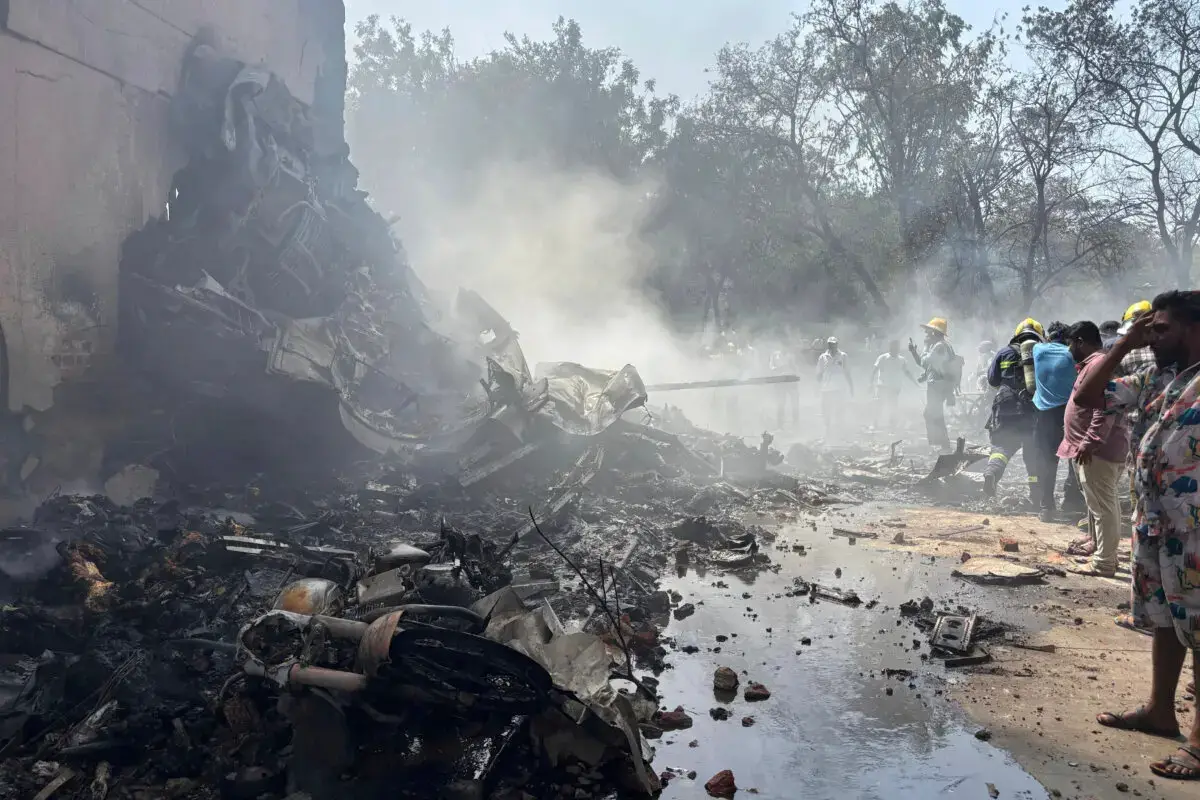 Personas cerca de los restos de un avión que se estrelló en la ciudad de Ahmedabad, en el estado de Gujarat, al noroeste de la India, el 12 de junio de 2025. (Ajit Solanki/AP Photo)