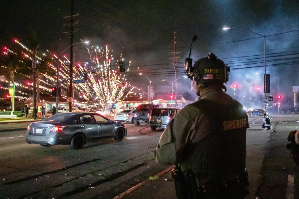 Un fuego artificial explota cerca de los agentes del Departamento del Sheriff de Los Ángeles en Paramount, California, el 7 de junio de 2025. (Apu Gomes/Getty Images)