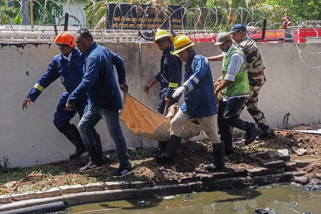Los bomberos transportan el cuerpo de una víctima tras el accidente del vuelo 171 de Air India, que se estrelló en una zona residencial cerca del aeropuerto de Ahmedabad, el 12 de junio de 2025. (SAM PANTHAKY/AFP a través de Getty Images)