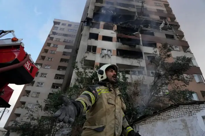 Un bombero llama a sus colegas en la escena de una explosión en un complejo residencial en el norte de Teherán, Irán, el 13 de junio de 2025. (Foto AP/Vahid Salemi)