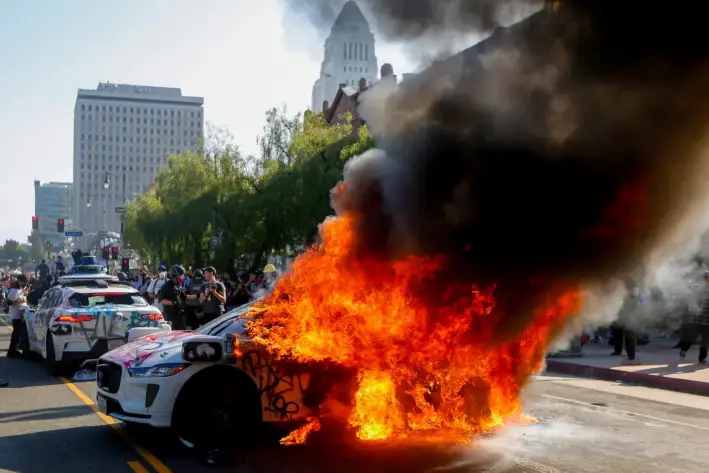 Las llamas envuelven un vehículo autónomo Waymo durante una protesta contra el ICE en el centro de Los Ángeles, el 8 de junio de 2025. (Benjamin Hanson/Middle East Images/AFP a través de Getty Images)