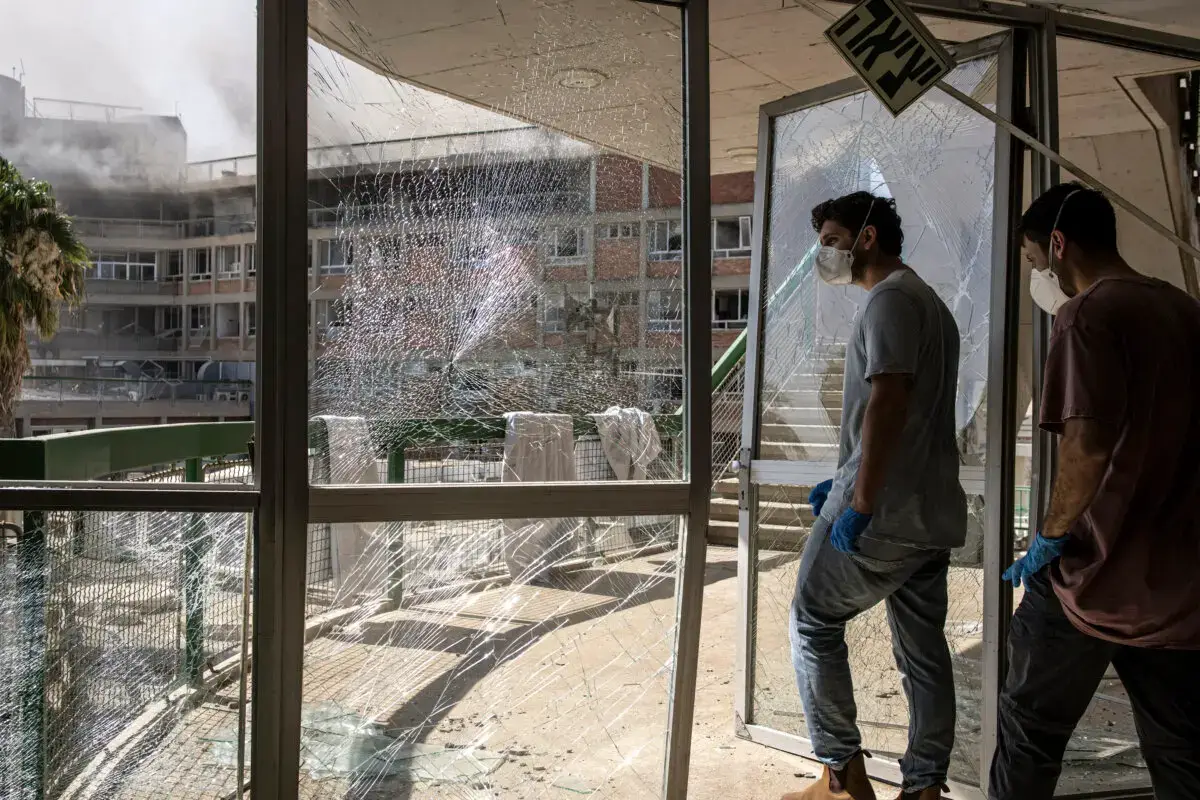 Los servicios de emergencia caminan a través de una puerta destruida en un edificio del Hospital Soroka después de que las instalaciones fueran alcanzadas por un misil iraní en Beersheba, en el sur de Israel, el 19 de junio de 2025. (John Wessels/AFP a través de Getty Images)