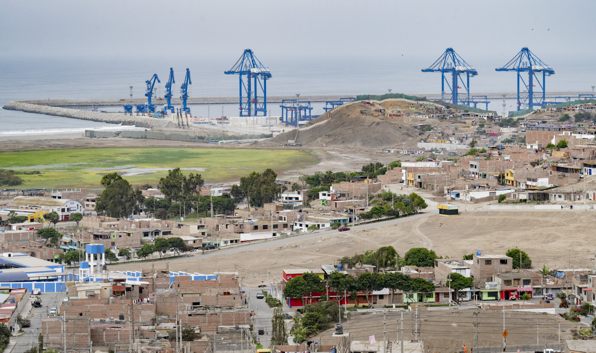 <em>Vista de las grúas del «megapuerto» de Chancay detrás de los barrios de la localidad de Chancay, a 78 kilómetros al norte de la capital peruana, Lima, el 29 de octubre de 2024. (CRIS BOURONCLE/AFP a través de Getty Images)</em>