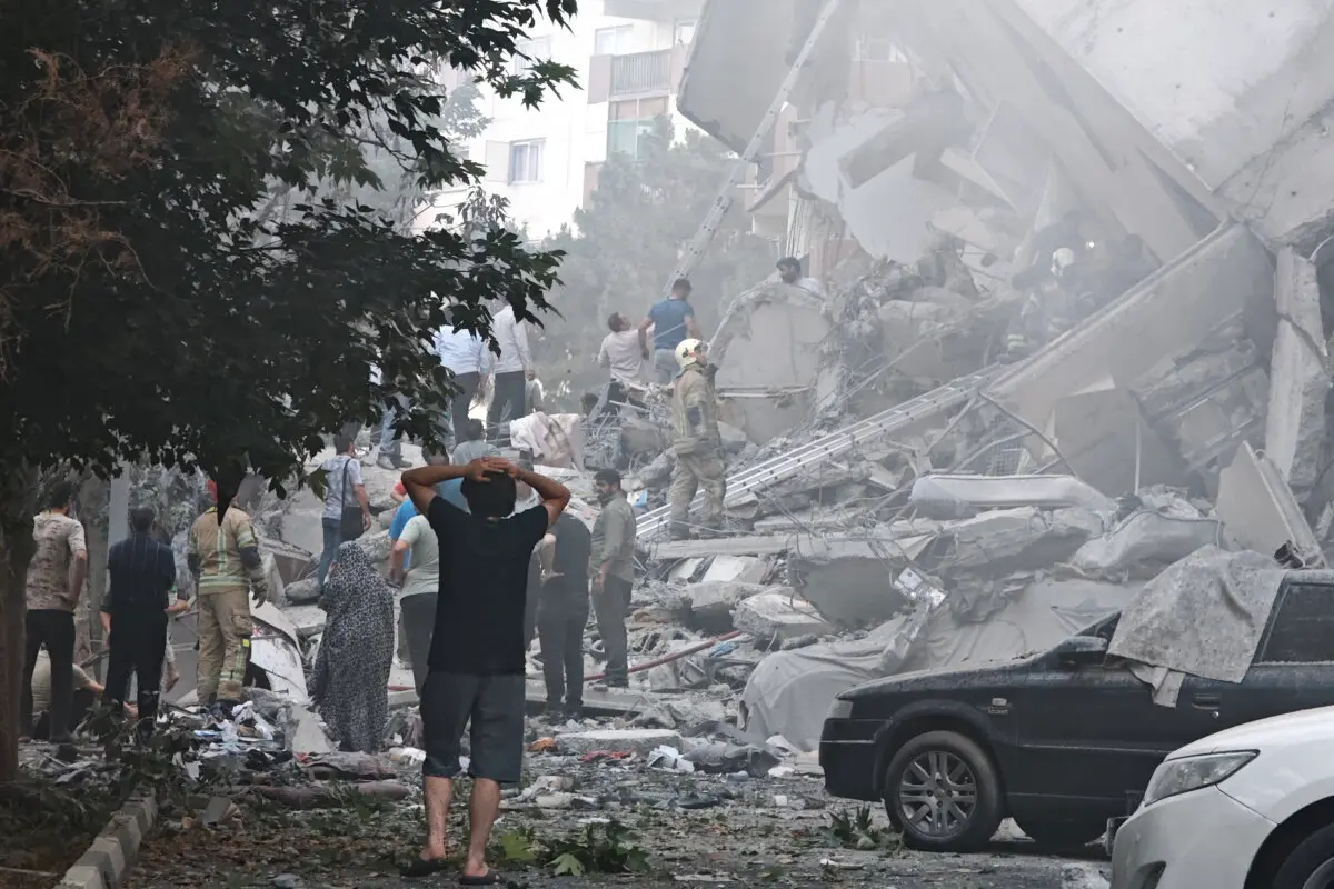 La gente observa los daños causados en los edificios tras los ataques aéreos israelíes contra instalaciones nucleares y militares en todo el país, en la plaza Nobonyad de Teherán, Irán, el 13 de junio de 2025. (Majid Saeedi/Getty Images).