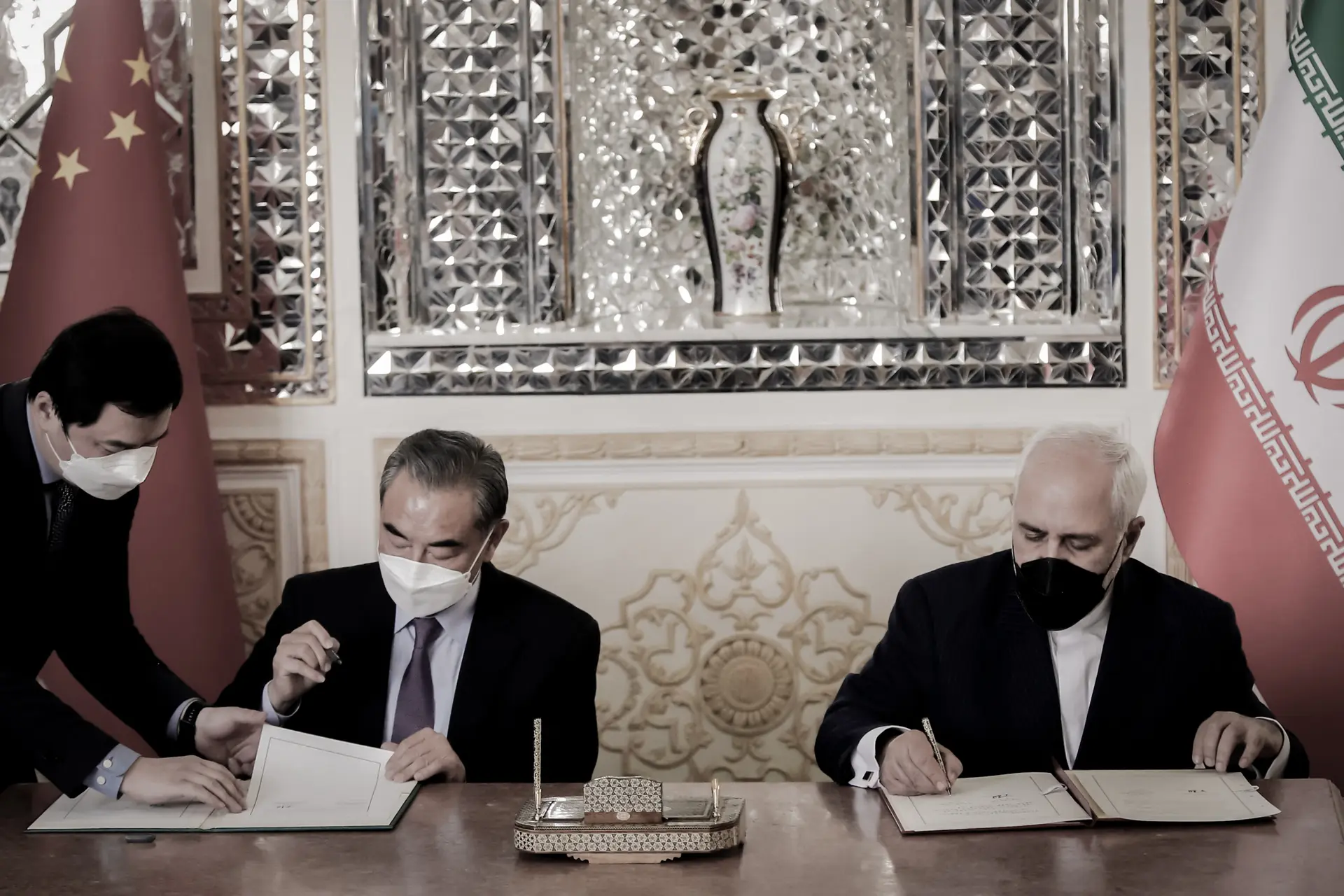 El ministro de Asuntos Exteriores iraní, Mohammad Javad Zarif (derecha), y su homólogo chino, Wang Yi (centro), firman un acuerdo en la capital iraní, Teherán, el 27 de marzo de 2021. China e Irán firmaron en 2021 el Programa de Cooperación Irán-China para los próximos 25 años, una alianza que, según algunos analistas, profundiza la dependencia económica de Irán respecto a Beijing. (AFP a través de Getty Images).