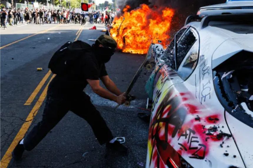 Un manifestante rompe la ventana de un vehículo de Waymo durante una manifestación tras las operaciones federales de control de la inmigración en Los Ángeles. Los manifestantes incendiaron coches y se enfrentaron a las fuerzas de seguridad el 8 de junio de 2025, mientras la policía los mantenía alejados de las tropas de la Guardia Nacional enviadas por el presidente Donald Trump. (Blake Fagan/AFP a través de Getty Images)