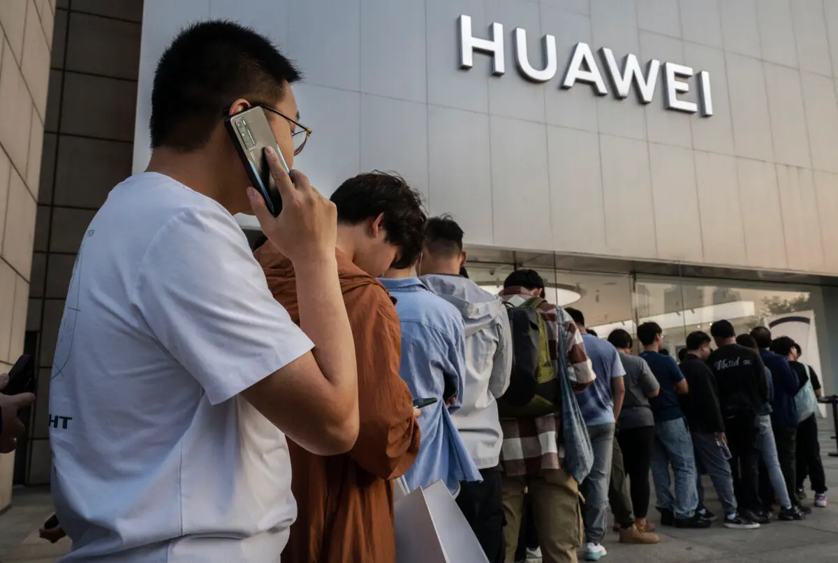 Un hombre habla por un teléfono móvil Huawei mientras él y otras personas hacen cola para comprar o reservar un nuevo smartphone Mate 60 y otros productos fuera de una tienda insignia de Huawei después de que la empresa presentara nuevos productos el 25 de septiembre de 2023 en Beijing, China. (Kevin Frayer/Getty Images)