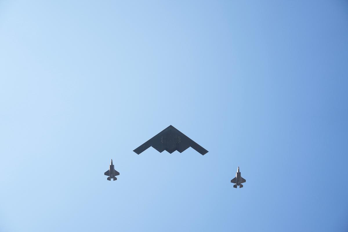Bombarderos B-2 sobrevuelan la Casa Blanca mientras el presidente de los Estados Unidos, Donald Trump, se pone en pie para escuchar el himno nacional durante un picnic militar familiar con motivo del Día de la Independencia en el jardín sur de la Casa Blanca, en Washington, el 4 de julio de 2025. (Eric Lee/Getty Images)