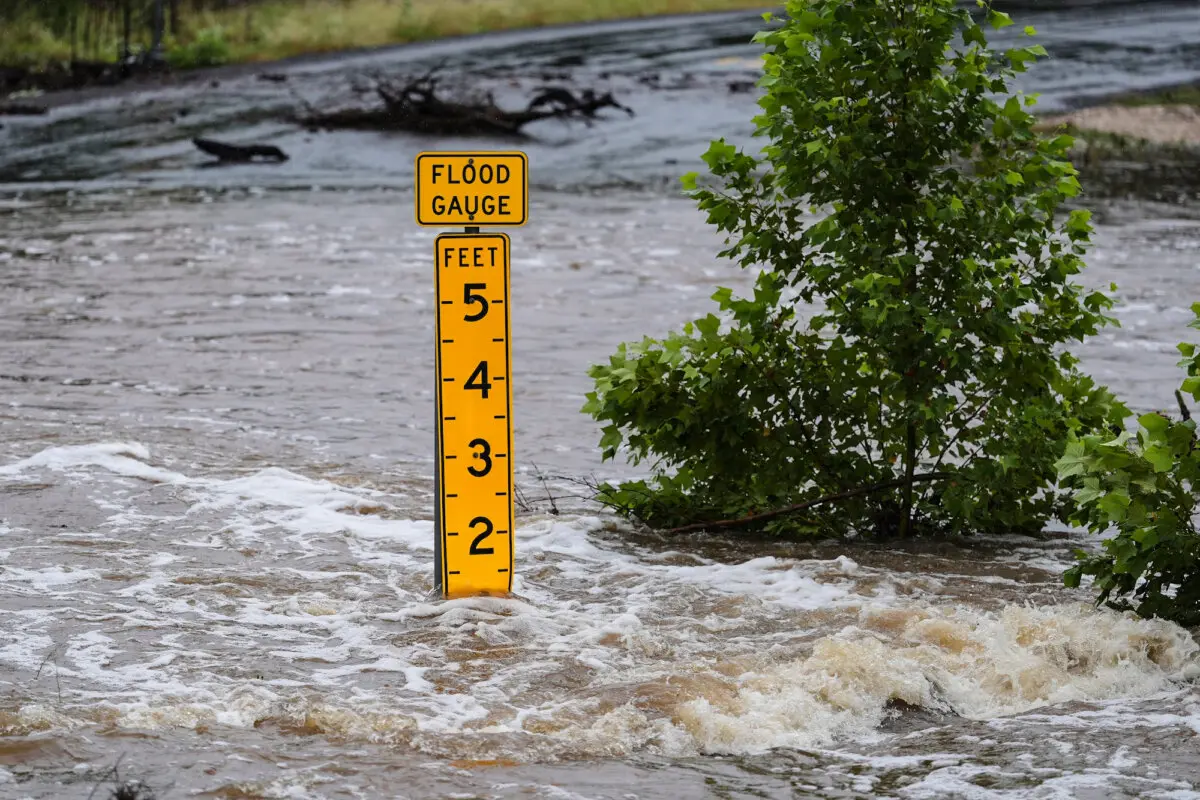 Un medidor de inundaciones marca la altura del agua que fluye por una carretera que une una granja con el mercado cerca de Kerrville, Texas, el 4 de julio de 2025. (Eric Gay/AP Photo)