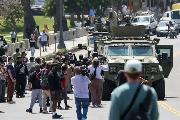 La gente observa a los agentes de Aduanas y Protección Fronteriza en un vehículo blindado por Wilshire Boulevard, cerca de MacArthur Park, en Los Ángeles, el 7 de julio de 2025. (Patrick T. Fallon/AFP a través de Getty Images)