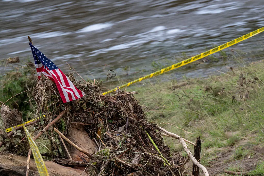 Una bandera estadounidense ondea sobre la cinta de precaución en las orillas del río Guadalupe, en Kerrville, Texas, el 6 de julio de 2025. (Brandon Bell/Getty Images).